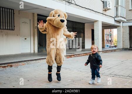 Ein kleiner Junge spielt mit einem riesigen Teddybären. Stockfoto