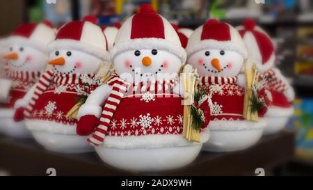 Ein Spielzeug Schneemann in einem roten Pullover und Hut holding Holz- Skier in den Händen. Neues Jahr Weihnachtsschmuck. Grußkarte mit schneemänner Stockfoto