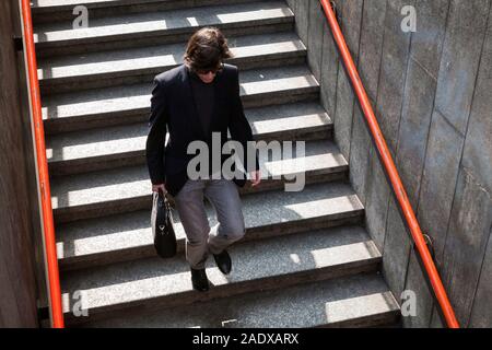 Gut aussehende junge Mann mit einer Tasche in der Hand ist im Untergeschoss auf dem Weg zur U-Bahn Station in Mailand, Italien Stockfoto