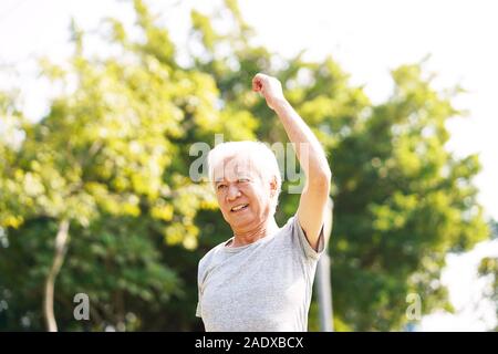 Gesunde ältere asiatischer Mann zu Fuß trainieren stretching Arms im Freien Stockfoto