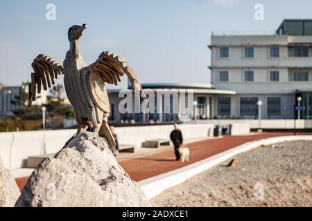 Morecambe Kormoran Skulpturen. Auf dem steinernen Steg in der Lancashire Stadt am Meer mit der Promenade und Art déco-Midland Hotel hinter sich. Stockfoto