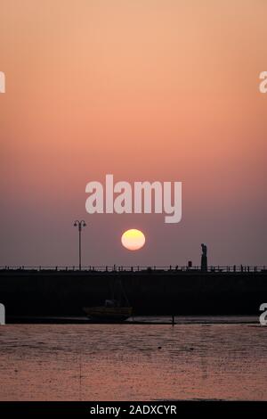 Sonnenuntergang in der Bucht von Morecambe, Lancashire, UK. Ein Blick über den Sandstrand von Morecambe Bay wie die Sonne über den steinernen Steg am Ende des Tages setzt. Stockfoto