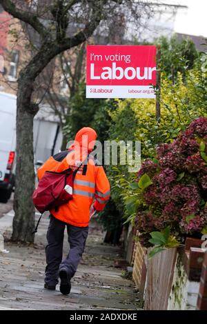 London, Großbritannien. 5 Dez, 2019. Ein briefträger Wanderungen vorbei an einer Labour Party Board für die allgemeinen Wahlen im Norden von London. Credit: Dinendra Haria/SOPA Images/ZUMA Draht/Alamy leben Nachrichten Stockfoto