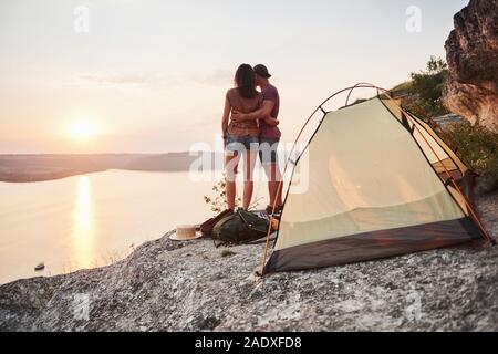 Foto von glücklich in der Nähe von Zelt mit Blick auf den See während der Wanderung. Reisen Abenteuer Urlaub Konzept Stockfoto
