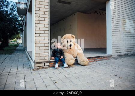 Ein kleiner Junge spielt mit einem riesigen Teddybären. Stockfoto