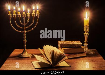 Menorah mit sieben brennende Kerzen, Leuchter und alte Bücher. Stockfoto