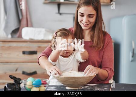 Das kleine Mädchen Hände in das Mehl. Mutter lehrt Tochter die Eier für das Osterfest zu malen Stockfoto