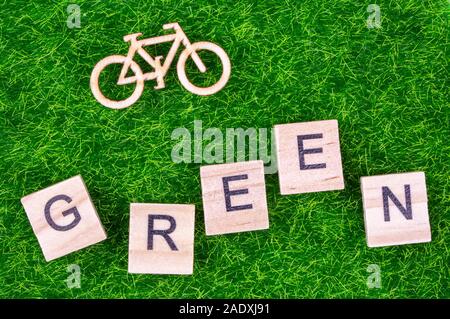 Eco transport Konzept mit Holz- Bike und Wort "Grün" in Holz Buchstaben auf dem Gras gelegt geschrieben Stockfoto