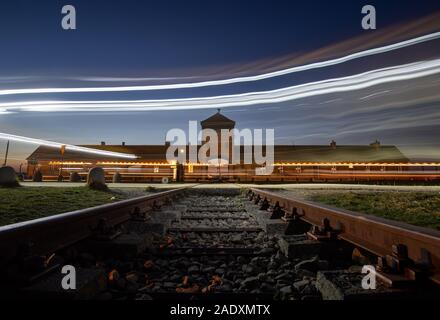 05 Dezember 2019, Polen, Oswiecim: Scheinwerfer von vorbeifahrenden Autos können vor dem Eingang Portal der ehemaligen Konzentrationslager Auschwitz-Birkenau gesehen werden. Bundeskanzlerin Angela Merkel (CDU) wird die Gedenkstätte im ehemaligen deutschen Konzentrationslager für den ersten Besuch am 06.12.2019. Es ist somit die Annahme einer Einladung der Stiftung Auschwitz-Birkenau anlässlich seines 10-jährigen Bestehens. (Schießen mit lange Belichtung) Foto: Robert Michael/dpa-Zentralbild/dpa Stockfoto