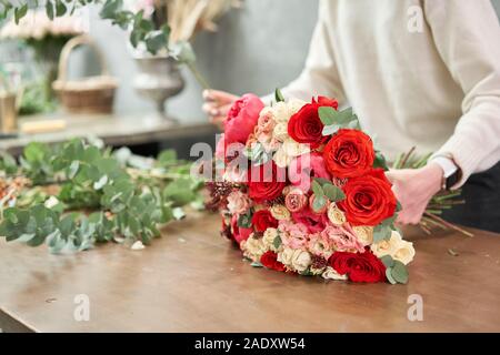 Europäische floral Shop Konzept. Floristin Frau schafft Red schöner Blumenstrauß aus gemischten Blumen. Schönen frischen Haufen. Bildung, master class und Stockfoto
