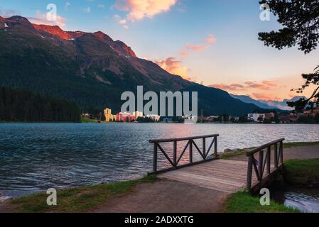 Sonnenuntergang über St. Moritz mit See auch genannt St. Moritzsee, ein Holzsteg im Vordergrund und Schweizer Alpen im Hintergrund im Engadin, Switze Stockfoto