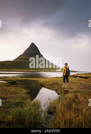 Junge Wanderer mit Rucksack schaut die Kirkjufell Berg Islands. Dieser 463 m hohe Berg liegt an der Nordküste Islands Snæfells entfernt Stockfoto