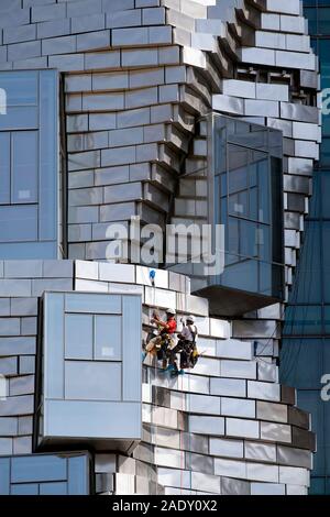 Zwei Arbeiter hängend Abseilen/Abseilen während der Reinigung Platten auf Frank Gehry LUMA Foundation Gebäude, Luma kulturelles Zentrum von Arles, Arles, Frankreich Stockfoto