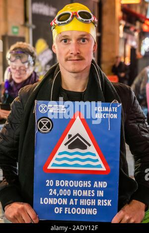 London, Großbritannien. 5 Dez, 2019. LONDON, UNTER WASSER U-BAHN! Aussterben Rebellion, 2030 Unterwasser Reise quer durch London auf den 'überflutet' central Line in Schnorchel und Flossen und endet bei der BBC über den Oxford Circus Station für eine endgültige Unwetterwarnung Wettervorhersage von einem special guest, Emma Thompson. Das Aussterben Rebellion 12 Tage der Krise das Klima und Ökologische Not ist ganz oben auf der Tagesordnung dieser Wahlen zu gewährleisten. Credit: Guy Bell/Alamy leben Nachrichten Stockfoto