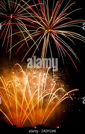 Buntes Feuerwerk am schwarzen Himmel Hintergrund über dem Wasser golden Stockfoto