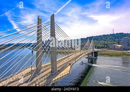 Tilikum Bridge überspannt den Fluss mit Blick auf den dichten Wald und den Blue Sky, Portland, Oregon Stockfoto