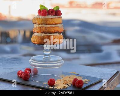 Frischkäse gefüllte Pfannkuchen garniert mit Himbeeren und gehobelten Mandeln auf einem Hintergrund von unfocused Küste. Stockfoto