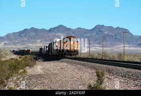 Barstow, Kalifornien - BNSF Freight Train verbindet die Lieferkette, die durch die Landschaft der Mojave-Wüste fährt und Güter und Ausrüstung mit der Bahn transportiert Stockfoto