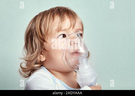 Kleinen niedlichen weißen kaukasische Mädchen, ca. 2 Jahre alt ist mit Zerstäuber einen Asthmaanfall zu stoppen. Kompressor Vernebler als Therapie für Atemwege dise Stockfoto