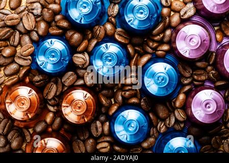 Bunte Espresso Kaffee Kapseln oder Pods auf Holz rustikale Hintergrund, Ansicht von oben. Die Kapseln sind in modischen Farben wie Gold und Blau Stockfoto