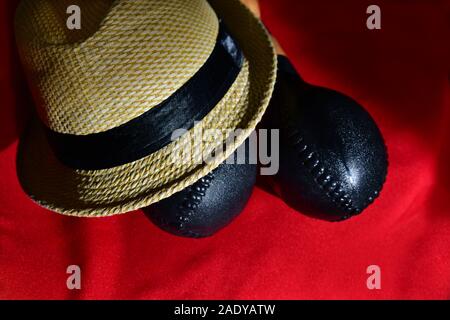 Typische kubanische Hut mit schwarzem Band neben Maracas auf einem roten Hintergrund. Stockfoto