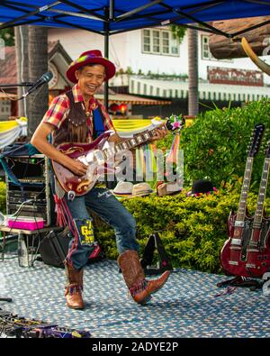 Ein asiatischer Mann gekleidet wie ein Cowboy Unterhaltung und Spielen einer Gitarre auf einem Markt in Thailand Stockfoto