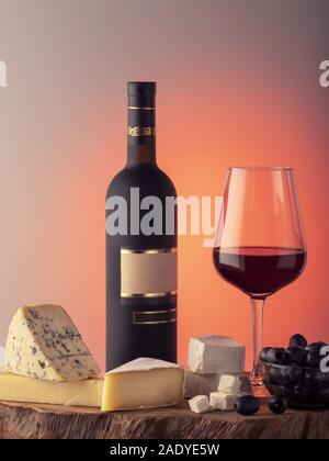 Eine Flasche Wein, ein Glas Rotwein, Käse und Trauben auf einem Holztisch. Stockfoto