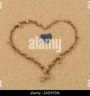 Liebe Herz (vom Fotografen) in Sand mit herzförmigen Stein in der Mitte am Sandstrand, Schottland, Großbritannien gezeichnet Stockfoto