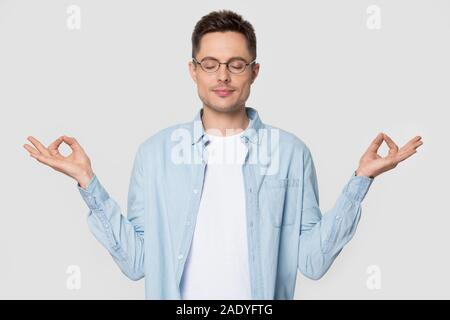 Entspannt tausendjährigen Mann, meditieren im Studio mit geschlossenen Augen Stockfoto