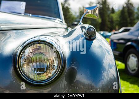 Helles Metall grau alten klassischen antiken amerikanischen Auto vorne, rechts, Nahaufnahme, Glas, Scheinwerfer mit Chrome Frame, verschwommenes Autos im Hintergrund Stockfoto