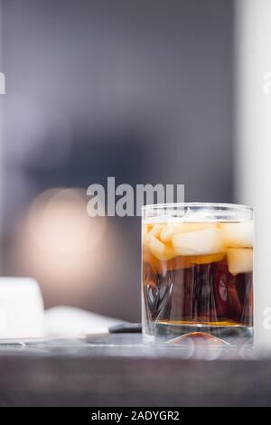 Nahaufnahme des Dunklen alkoholisches Getränk mit Eis auf den Felsen mit verschwommenen Hintergrund Stockfoto