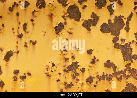 Close-up von Verwitterten gelb lackierte Oberfläche aus Metall mit großen und kleinen Roststellen. Stockfoto