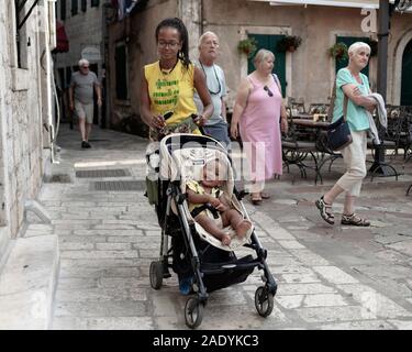 Kotor, Montenegro, 22. September 2019: Frau mit Baby, die in der Altstadt von Kotor die Straße hinunter läuft Stockfoto