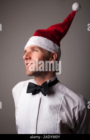 Portrait des jungen Mannes in formalen Black Tie tuxedo Weihnachten feiern in einem Santa Hut Stockfoto