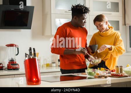 Sorgende Frau hinzufügen Salz Salat von Ihrem Freund Stockfoto