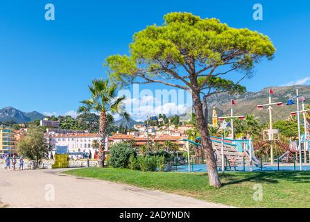 Touristen und Einheimische genießen einen sonnigen Tag an der französischen Riviera, während sie sich am Meer im Fossan Beach Park in Menton, Frankreich, entspannen.