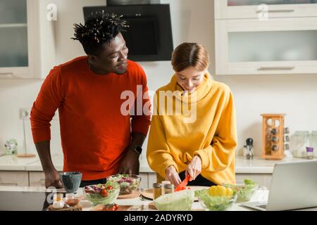 Positive lady Schneiden von Gemüse und der junge Mann lächelnd Stockfoto