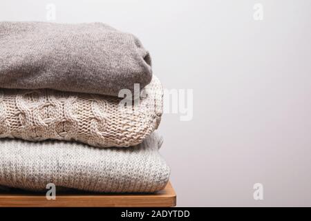 Stapel von warmen, aus Gewirken aus Wolle Pullover gegen weiße Wand Stockfoto