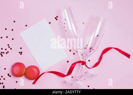 Zwei Sektgläser, Macarons und herzförmige Konfetti auf rosa Hintergrund. Stockfoto