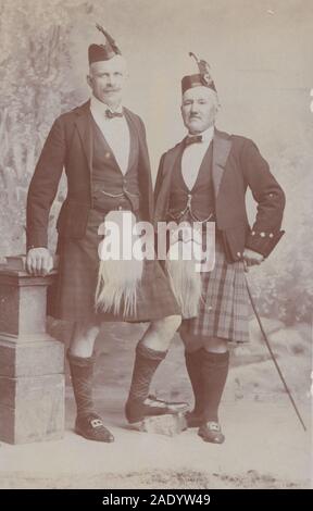 Vintage Anfang des 20. Jahrhunderts Fotopostkarte im Studio zeigt zwei schottische Männer, die ihre Kilts und Sporran tragen. Stockfoto