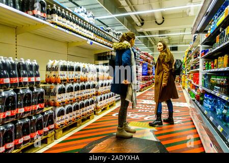 Zwei junge Frauen in den Supermarktregalen, Getränkeabteilung im Tesco Store-weite Ansicht Supermarktregale ohne Preis Stockfoto