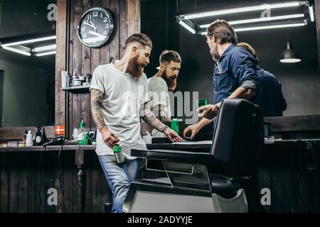Zwei Männer betrachten Haarschneider klingen im barbershop Stockfoto