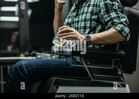 Mann in kariertem Hemd sitzen und halten Glas Whiskey Stockfoto