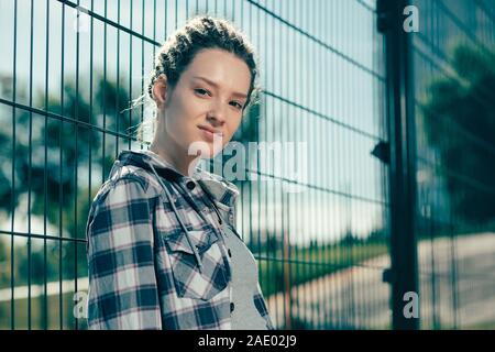 Porträt der schönen Dame lächelnd und stand in der Nähe der Maschendrahtzaun Stockfoto