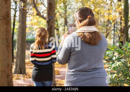 Rückansicht einer jungen Frau mit Smartphone von jungen Frau Modell im Außenbereich Stockfoto