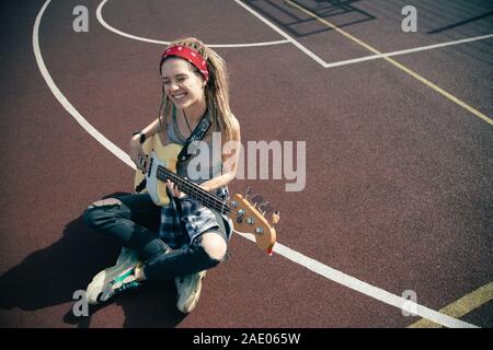 Blick von oben auf die glückliche Dame lächelnd und Gitarre spielen Stockfoto