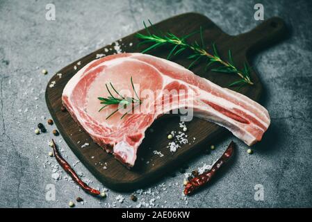 Frische rohe Schweinerippchen Steak mit Kräuter und Gewürze Rosmarin/Frisches Fleisch Schweinefleisch in Scheiben geschnitten auf Holz Schneidebrett Hintergrund Stockfoto