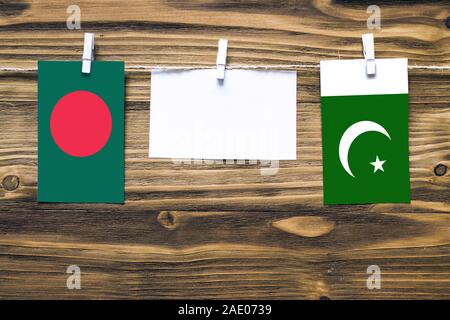 Hängenden Flaggen von Bangladesch und Pakistan zu Seil mit wäscheklammer mit Kopie Raum befestigt auf weißem Papier auf Holz- Hintergrund. diplomatischen Relati Stockfoto