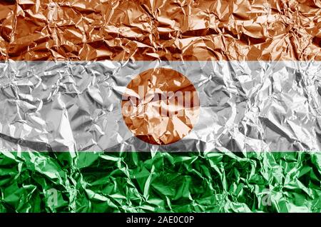 Niger Fahne in Farbe Farben dargestellt auf glänzenden zerknüllter Alufolie hautnah. Texturierte Banner auf rauen Hintergrund Stockfoto