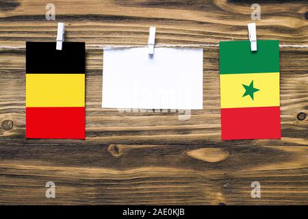Hängenden Flaggen Belgien und Senegal zu Seil mit wäscheklammer mit Kopie Raum befestigt auf weißem Papier auf Holz- Hintergrund. Diplomatische Beziehungen Stockfoto